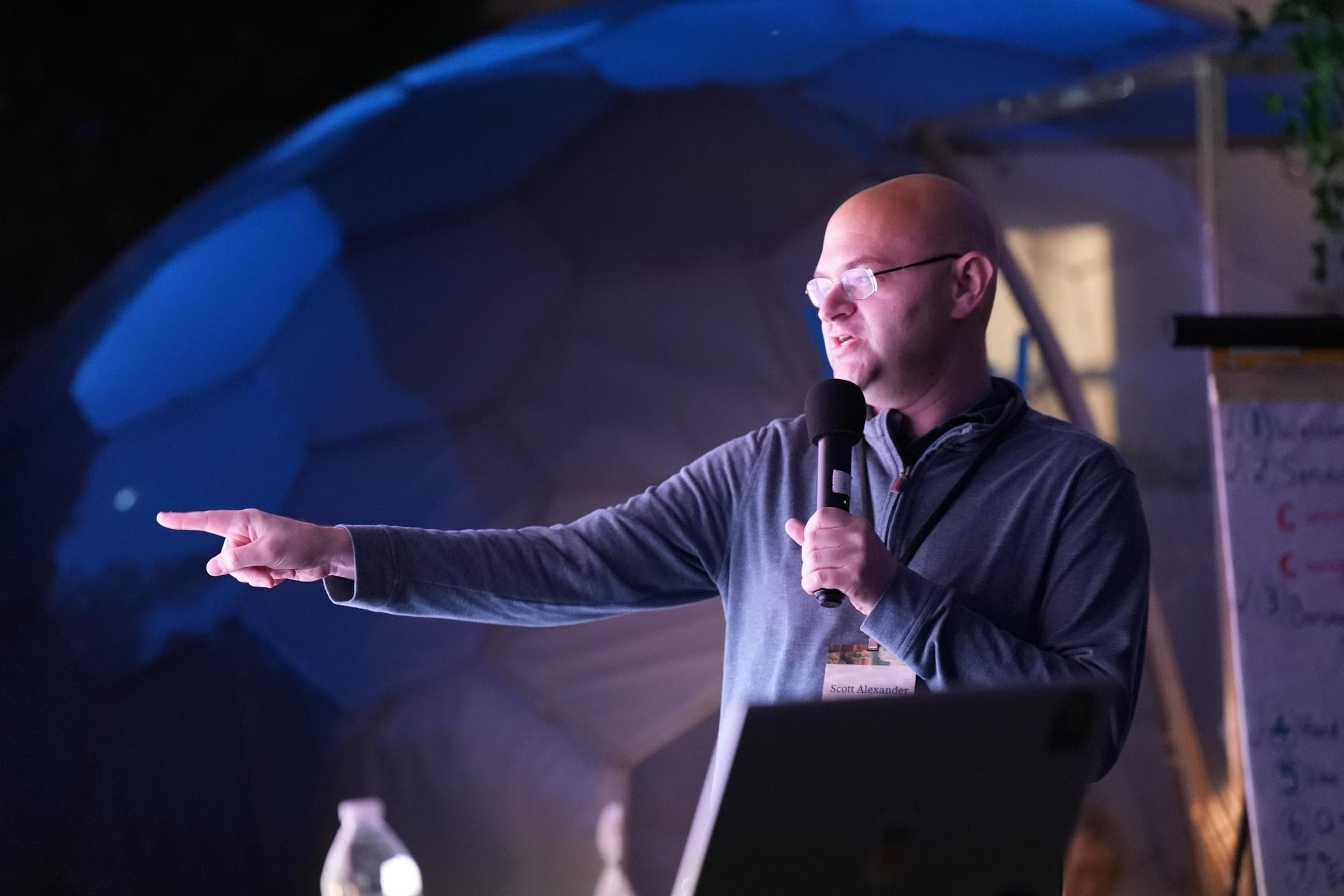 A LessOnline speaker gives a talk to an outdoor audience.