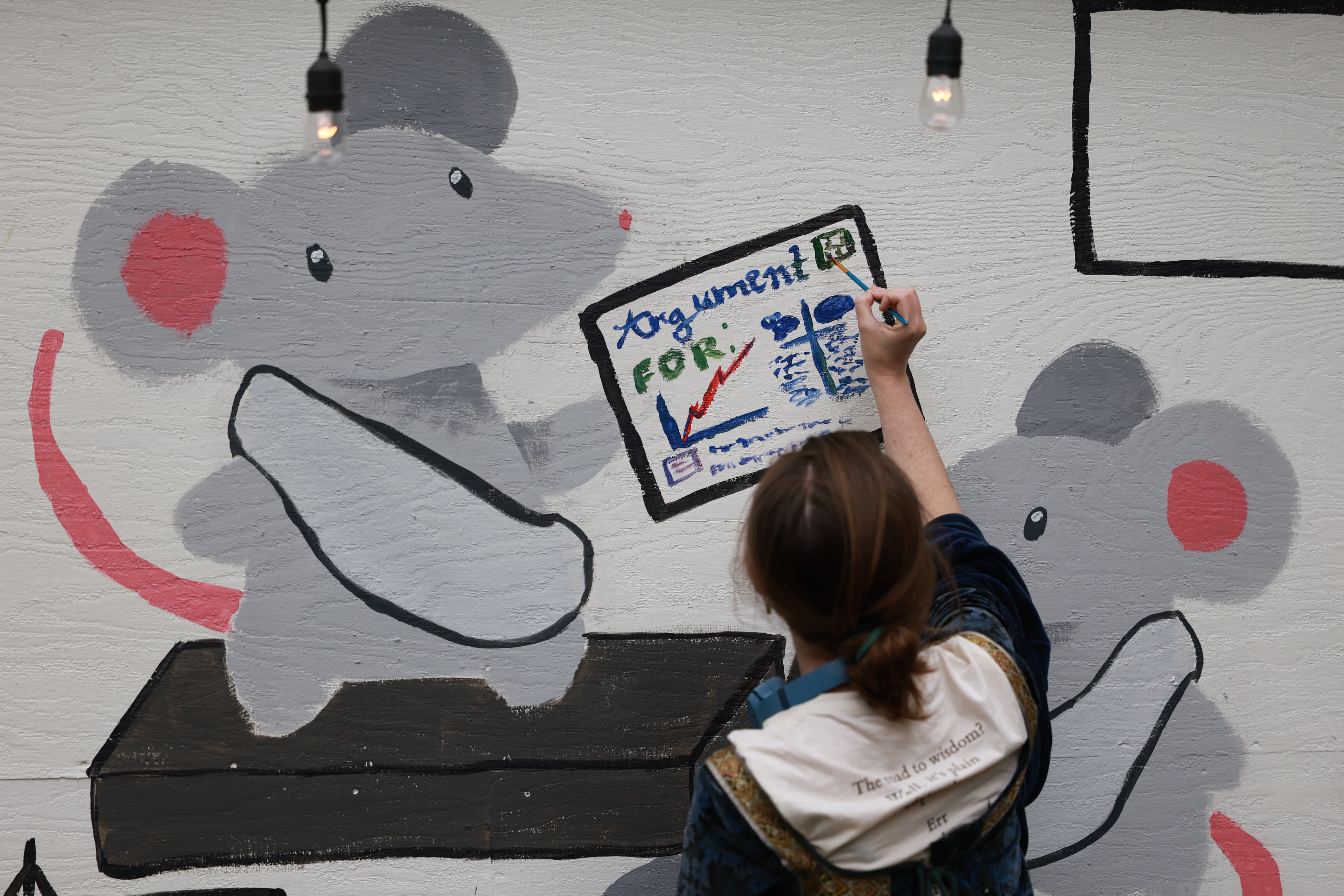 Close-up of someone painting a hand-drawn Argument FOR chart onto the mouse mural.